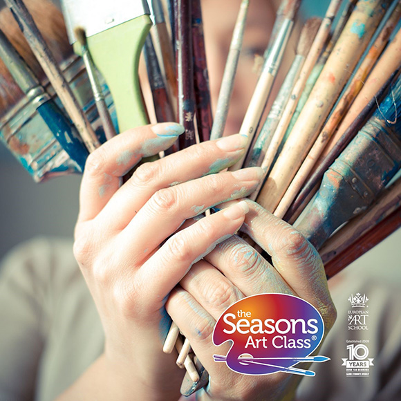 hands holding various paintbrushes with paint smudges showcasing creativity and artistic tools in an art class setting